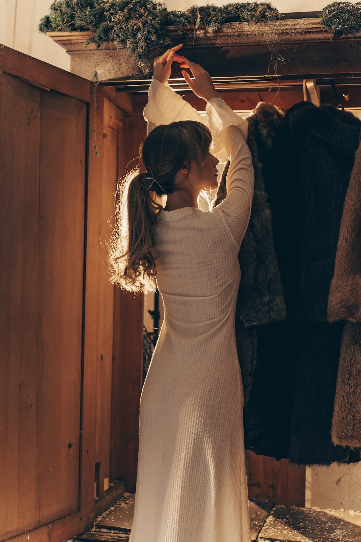 Picking a dress from a wooden wardrobe